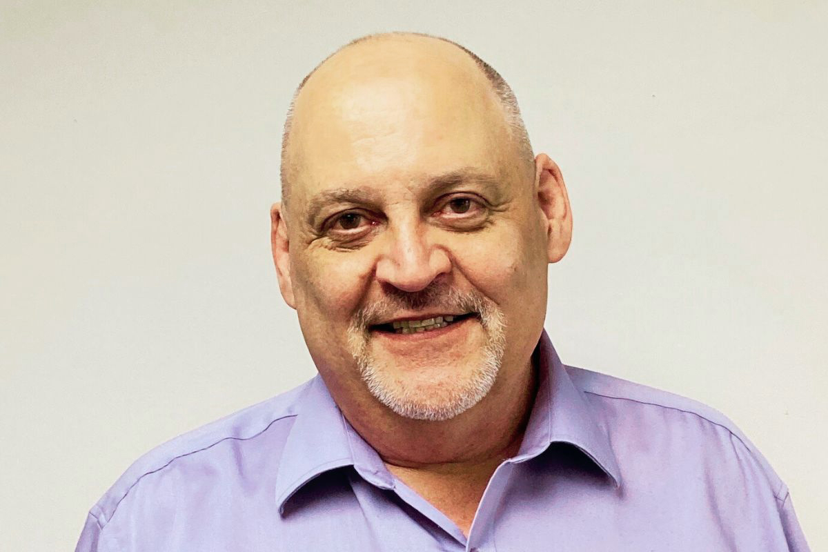 Kevin Lussier smiling in a light purple collared shirt.