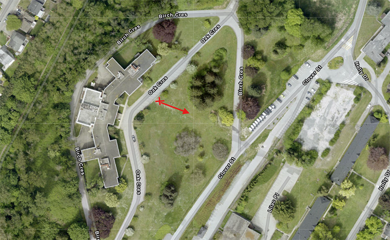 Aerial view of a residential neighborhood in Kamloops with labeled streets including Birch Cres, Oak Cres, Glover St, and Unce Pl. A red arrow highlights an open grassy area near Oak Cres and Glover St, adjacent to a large building complex surrounded by greenery.